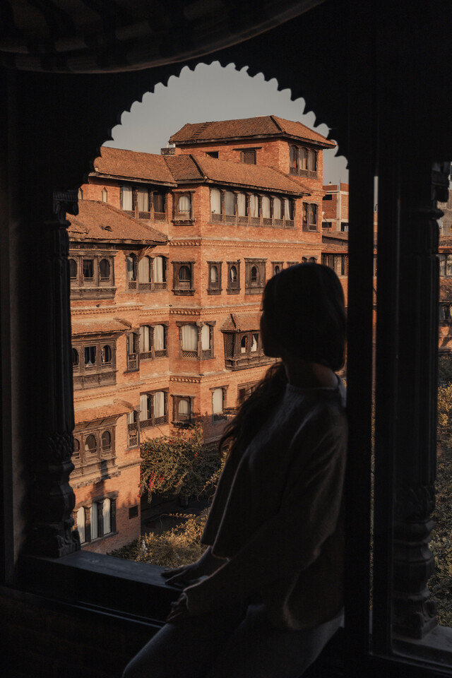From the window, the courtyard unfolds in carved wood and ancient symmetry . Framed in quiet comfort.