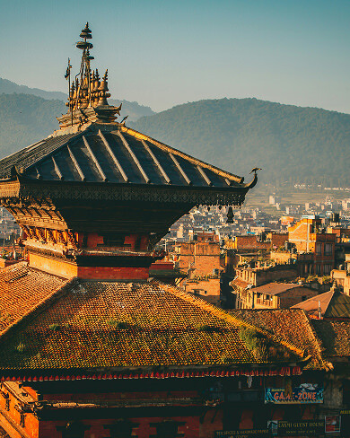 Golden hour view of Kathmandu temple rooftops with mountains in background