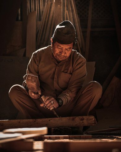 Master craftsman carving wood using traditional Newari techniques