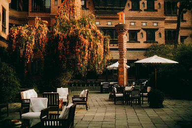 Courtyard terrace with seating under flowering orange vines and heritage brick buildings