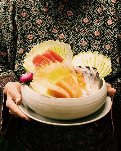 Fresh sashimi platter with carved melon presented on handcrafted ceramic bowl