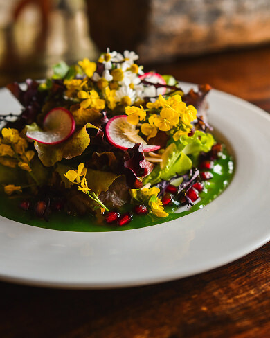 Garden salad with edible flowers and radish on white plate